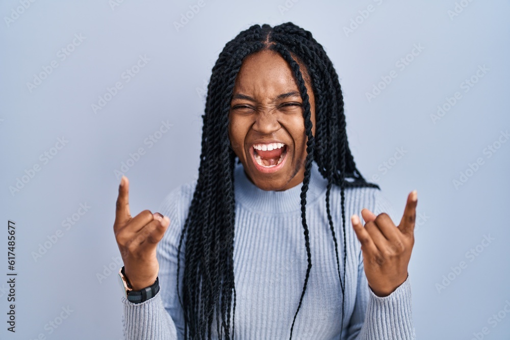 Poster african american woman standing over blue background shouting with crazy expression doing rock symbo