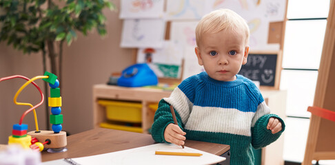 Adorable caucasian boy preschool student drawing on notebook at kindergarten