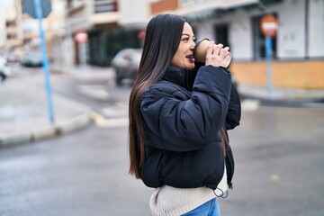 Fototapeta premium Young beautiful hispanic woman talking on smartphone drinking coffee at street