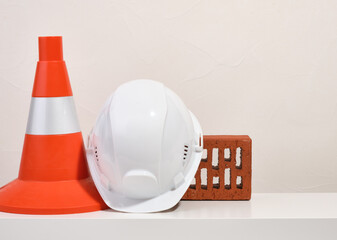 Construction cone, white head protection helmet and facing brick. Copy space for text.