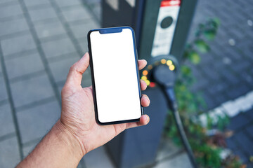 Man holding smartphone showing white blank screen at electrical car station