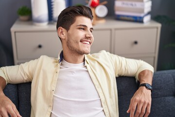 Fototapeta premium Young hispanic man smiling confident sitting on sofa at home