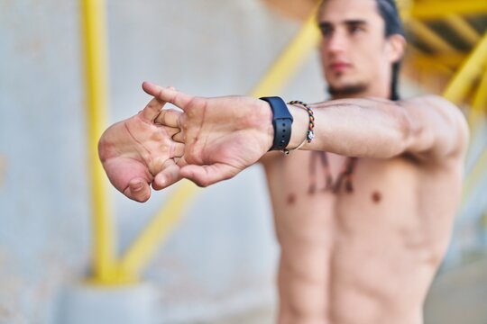 Young man stretching arms at street