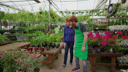 A male employee showing Flowers and Plants to female customer inside Flower Shop, local business concept