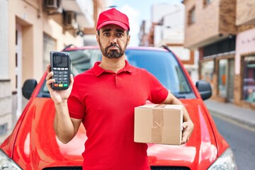 Young hispanic man with beard wearing delivery uniform and cap holding dataphone depressed and worry for distress, crying angry and afraid. sad expression.