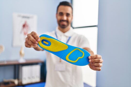 Young hispanic man podiatrist holding insole at podiatry center