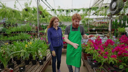 A male employee showing Flowers and Plants to female customer inside Flower Shop, local business concept