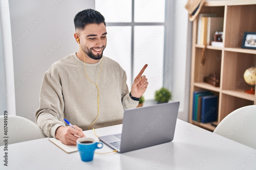 Sticker Young handsome man using computer laptop doing online call smiling happy pointing with hand and finger to the side