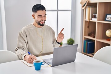 Young handsome man using computer laptop doing online call smiling happy pointing with hand and...