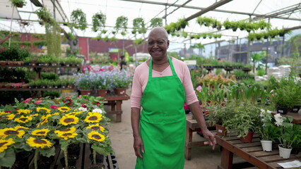 Obraz premium A happy Brazilian Senior Employee in Green Apron Strolling Through a Vibrant Flower Shop smiling
