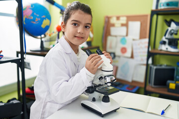 Adorable hispanic girl student smiling confident using microscope at laboratory classroom