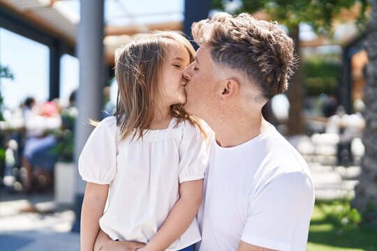 Father and daughter standing together kissing at street
