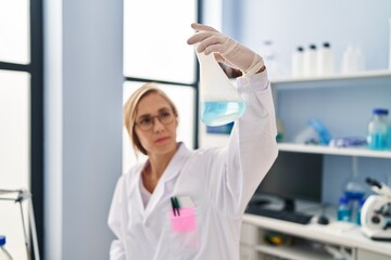 Young blonde woman scientist holding test tube at laboratory