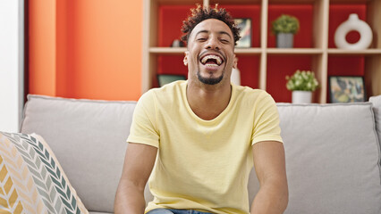 African american man smiling confident sitting on sofa speaking at home