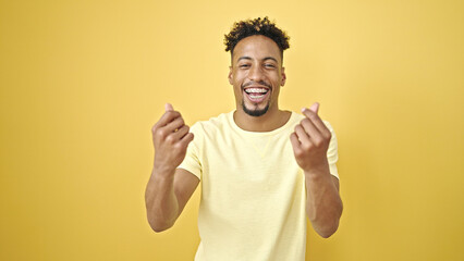 African american man smiling confident doing money gesture over isolated yellow background