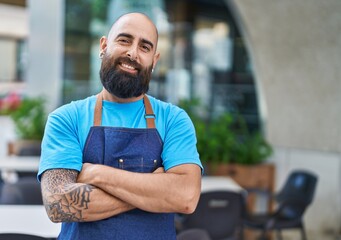 Young bald man waiter smiling confident standing with arms crossed gesture at coffee shop terrace