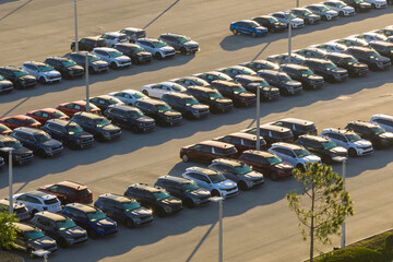 Large parking lot of local dealer with many brand new cars parked for sale. Development of american...