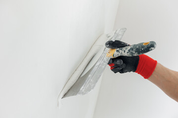 Closeup hands man drywall worker using trowel for plasterer putting stucco on plasterboard white...