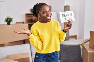 Beautiful black woman moving to a new home celebrating achievement with happy smile and winner expression with raised hand