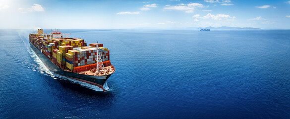 Panoramic front view of a large cargo ship carrying containers for import and export, business logistic and transportation in open sea with copy space  - 617494046