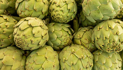 Fototapeta premium close up of large amount of artichokes for sale at the market