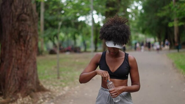 Tired exhausted dehydrated Athlete black woman runner drinking water bottle after workout. Sports bottle drink. female sportswoman. runner sweaty and thirsty after difficult jogging outdoors in city p