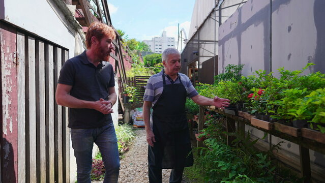 Senior Gardener Assisting Customer at Plant Store. Horticulturist culture in Flower Shop backyard of senior person showing plants to young man