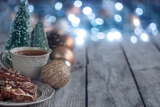 Christmas chocolate cookies on wooden table with tea, balls and defocused lights. Copyspace background.