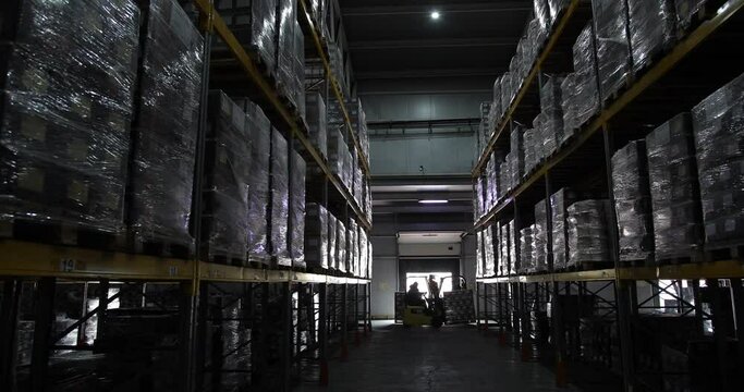 Warehouse large logistics commerce structure with boxes on shelves. Teamwork male person industrial production using working machines and vehicles delivering goods for transnational export indoors