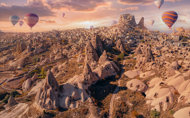 Ancient Uchisar castle at sunset, Cappadocia Turkey landscape with color hot air balloons. Aerial...
