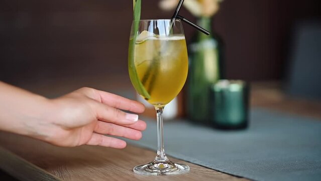 The bartender puts a beautiful refreshing cocktail on the table.
