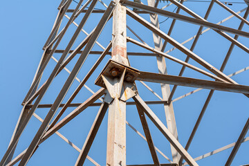 A steel pole for high voltage transmission is photographed against a cloudless sky with a bolted connection in the center of the frame.