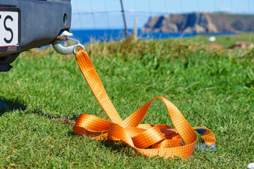 Tow hook with orange strap on car. Towing equipment.