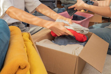 Woman and child sorting clothes and packing into cardboard box. Donations for charity, help low...
