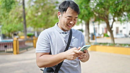  using smartphone and earphones smiling at park