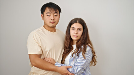 Man and woman couple hugging each other with serious expression over isolated white background