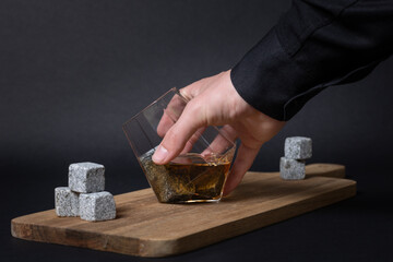 diamond whisky glass with rocks and wisky poured in, on wooden serving tray. Being picked up by...