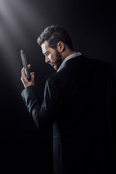 Brave cool man holding a gun on dark background