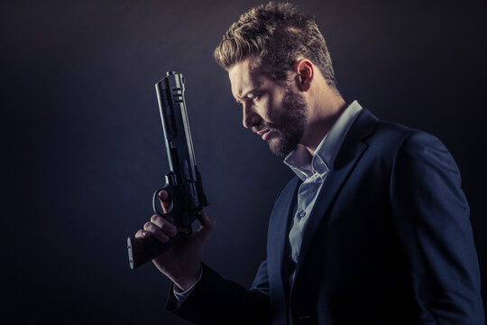 Brave cool man holding a dangerous weapon on dark background
