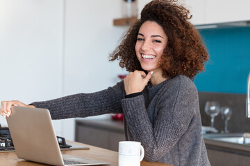 laughter of a woman using a portable personal computer in her kitchen