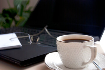 Work desk with laptop computer and hot coffee cup with defocused background