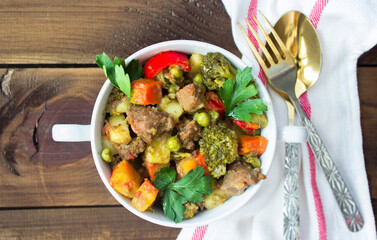 served beef meat stewed with potatoes, carrots and spices in ceramic pot on wooden background