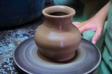 A clay pot on a pottery wheel, pottery craft, moulding the pot with your hands, sculpting hands