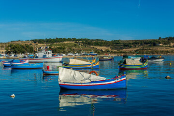 Colorful painted wood boats with the typical protective eyes on a sunny day in Marsaxlokk, Malta.