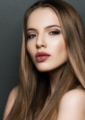 Fototapeta premium Beautiful woman model portrait with long hair on dark background. Red lips