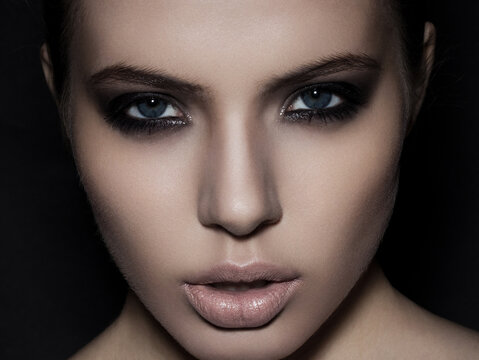Beautiful woman model smokey eyes makeup close up on black background