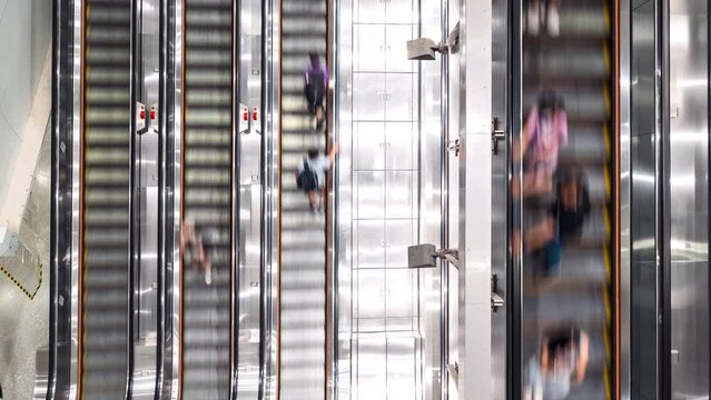 Time-lapse of Asian people transport on escalator at subway underground station in Hong Kong. Public transportation, Asia city life, or commuter urban lifestyle concept. Top high angle view, tilt down