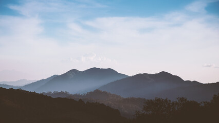 Foggy mountain range in low key tone with cloudy blue sky - Powered by Adobe
