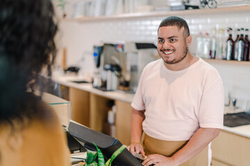 Brazilian man smiling working at a coffee shop in Brazil using computer