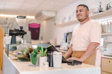 Brazilian man smiling working at a coffee shop in Brazil using computer